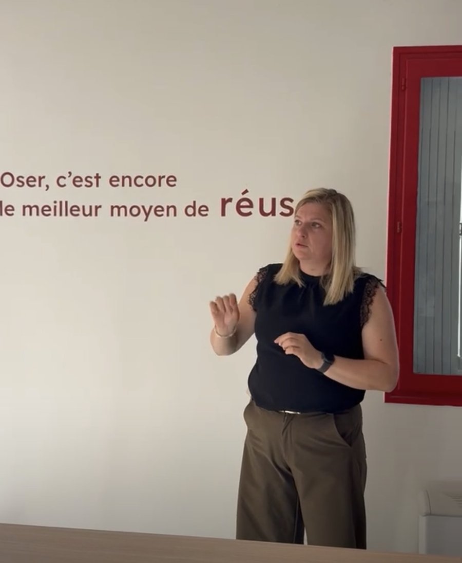 Emilie Giraud debout devant un mur portant la phrase&nbsp;: Oser, c'est encore le meilleur moyen de réussir